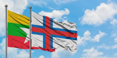Myanmar ve Faroe Adaları bayrağı birlikte beyaz bulutlu mavi gökyüzüne karşı rüzgarda sallayarak. Diplomasi kavramı, uluslararası ilişkiler.