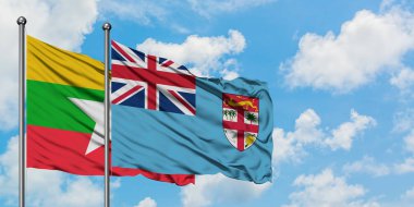 Myanmar ve Fiji bayrağı birlikte beyaz bulutlu mavi gökyüzüne karşı rüzgarda sallayarak. Diplomasi kavramı, uluslararası ilişkiler.