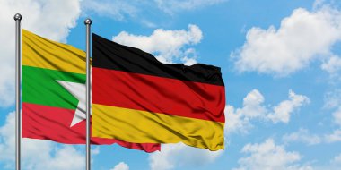 Myanmar ve Almanya bayrağı birlikte beyaz bulutlu mavi gökyüzüne karşı rüzgarsal sallayarak. Diplomasi kavramı, uluslararası ilişkiler.