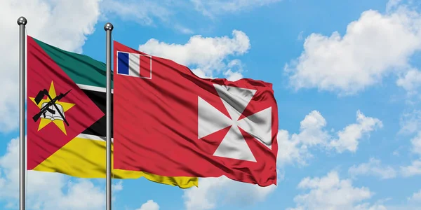 Mozambique y Wallis Y la bandera de Futuna ondeando en el viento contra el cielo azul nublado blanco juntos. Concepto diplomático, relaciones internacionales . — Foto de Stock