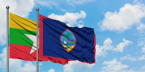 Bandera de Myanmar y Guam ondeando en el viento contra el cielo azul nublado blanco juntos. Concepto diplomático, relaciones internacionales . — Foto de Stock