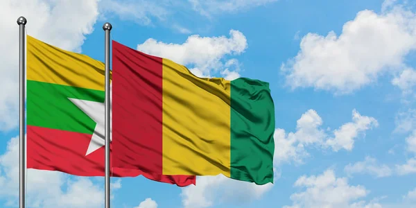 Bandera de Myanmar y Guinea ondeando en el viento contra el cielo azul nublado blanco juntos. Concepto diplomático, relaciones internacionales . — Foto de Stock