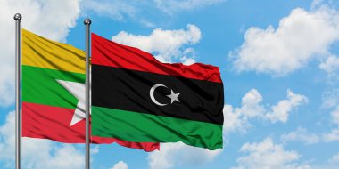 Myanmar ve Libya bayrağı birlikte beyaz bulutlu mavi gökyüzüne karşı rüzgarsal sallayarak. Diplomasi kavramı, uluslararası ilişkiler.