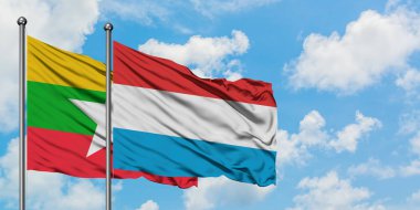 Myanmar ve Lüksemburg bayrağı birlikte beyaz bulutlu mavi gökyüzüne karşı rüzgarsal sallayarak. Diplomasi kavramı, uluslararası ilişkiler.