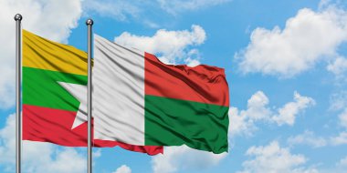 Myanmar ve Madagaskar bayrağı birlikte beyaz bulutlu mavi gökyüzüne karşı rüzgarda sallayarak. Diplomasi kavramı, uluslararası ilişkiler.