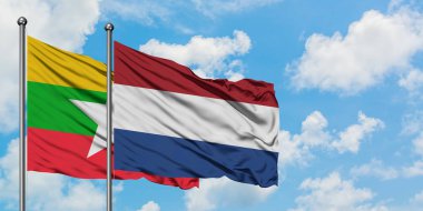 Myanmar ve Hollanda bayrağı birlikte beyaz bulutlu mavi gökyüzüne karşı rüzgarsal sallayarak. Diplomasi kavramı, uluslararası ilişkiler.