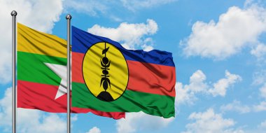 Myanmar ve Yeni Kaledonya bayrağı birlikte beyaz bulutlu mavi gökyüzüne karşı rüzgarda sallayarak. Diplomasi kavramı, uluslararası ilişkiler.