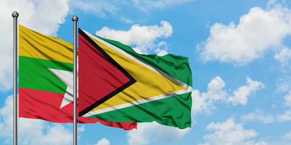 Bandera de Myanmar y Guyana ondeando en el viento contra el cielo azul nublado blanco juntos. Concepto diplomático, relaciones internacionales . — Foto de Stock