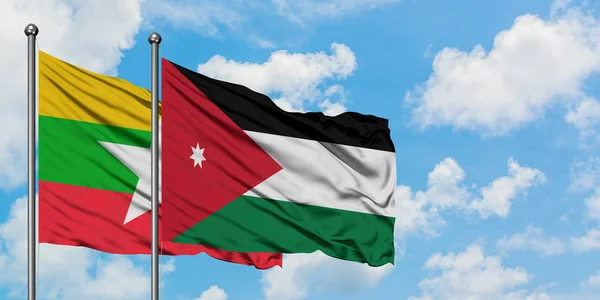 Bandera de Myanmar y Jordania ondeando en el viento contra el cielo azul nublado blanco juntos. Concepto diplomático, relaciones internacionales . — Foto de Stock