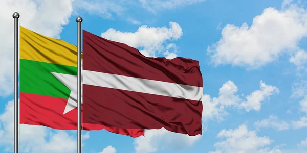 Mianmar és Lettország zászló integetett a szél ellen, fehér felhős kék ég együtt. Diplomáciai koncepció, nemzetközi kapcsolatok. — Stock Fotó