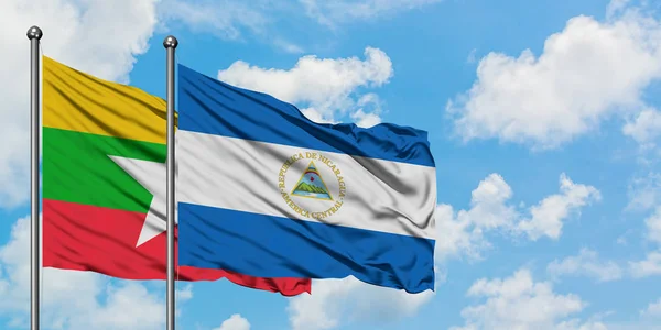 Bandera de Myanmar y Nicaragua ondeando en el viento contra el cielo azul nublado blanco juntos. Concepto diplomático, relaciones internacionales . — Foto de Stock