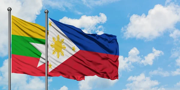 Bandera de Myanmar y Filipinas ondeando en el viento contra el cielo azul nublado blanco juntos. Concepto diplomático, relaciones internacionales . — Foto de Stock