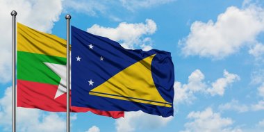 Myanmar ve Tokelau bayrağı birlikte beyaz bulutlu mavi gökyüzüne karşı rüzgarda sallayarak. Diplomasi kavramı, uluslararası ilişkiler.