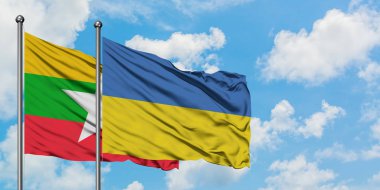 Myanmar ve Ukrayna bayrağı birlikte beyaz bulutlu mavi gökyüzüne karşı rüzgarsal sallayarak. Diplomasi kavramı, uluslararası ilişkiler.