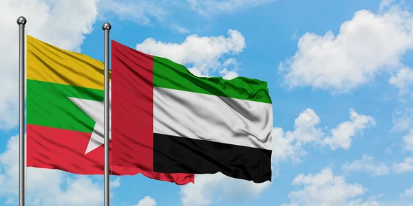 Birmania y los Emiratos Árabes Unidos ondean en el viento contra el cielo azul nublado blanco juntos. Concepto diplomático, relaciones internacionales . — Foto de Stock