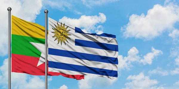 Bandera de Myanmar y Uruguay ondeando en el viento contra el cielo azul nublado blanco juntos. Concepto diplomático, relaciones internacionales . — Foto de Stock