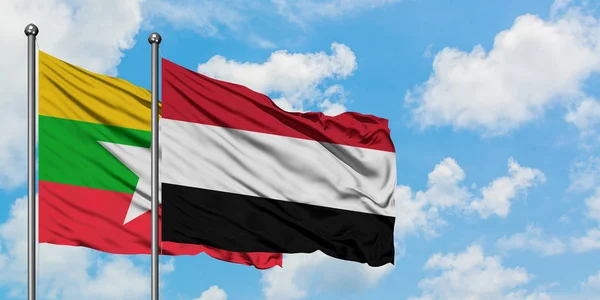 Bandera de Myanmar y Yemen ondeando en el viento contra el cielo azul nublado blanco juntos. Concepto diplomático, relaciones internacionales . — Foto de Stock