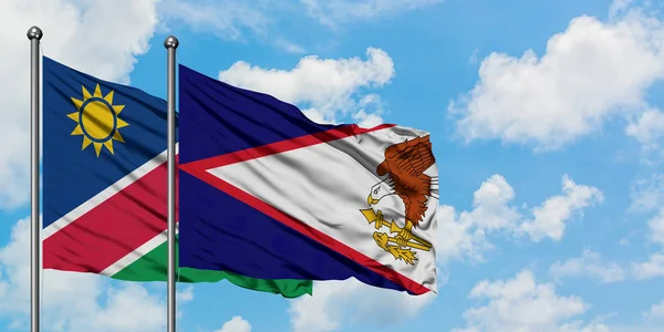 Drapeau namibien et samoa américaines agitant dans le vent contre le ciel bleu nuageux blanc ensemble. Concept de diplomatie, relations internationales . — Photo