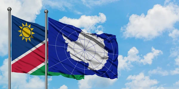 Bandera de Namibia y Antártida ondeando en el viento contra el cielo azul nublado blanco juntos. Concepto diplomático, relaciones internacionales . — Foto de Stock