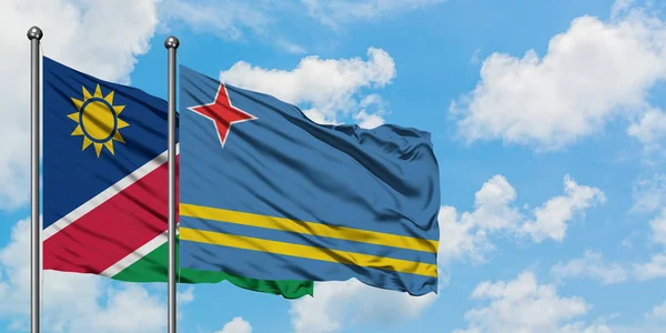Namíbia és Aruba zászló integetett a szél ellen, fehér felhős kék ég együtt. Diplomáciai koncepció, nemzetközi kapcsolatok. — Stock Fotó