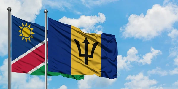 Bandera de Namibia y Barbados ondeando en el viento contra el cielo azul nublado blanco juntos. Concepto diplomático, relaciones internacionales . — Foto de Stock