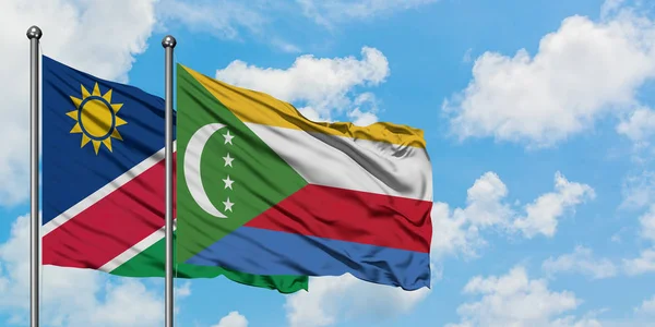 Namibya ve Komor bayrağı birlikte beyaz bulutlu mavi gökyüzüne karşı rüzgarda sallayarak. Diplomasi kavramı, uluslararası ilişkiler. — Stok fotoğraf
