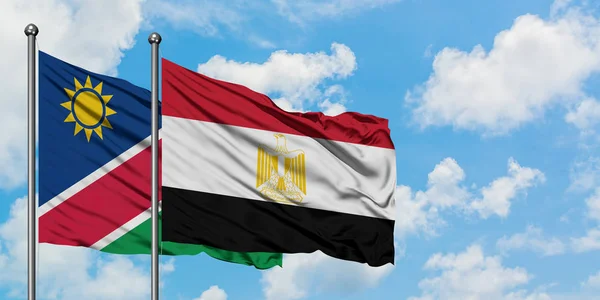 Bandera de Namibia y Egipto ondeando en el viento contra el cielo azul nublado blanco juntos. Concepto diplomático, relaciones internacionales . — Foto de Stock