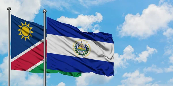 Bandera de Namibia y El Salvador ondeando en el viento contra el cielo azul nublado blanco juntos. Concepto diplomático, relaciones internacionales . — Foto de Stock
