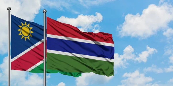 Drapeau de Namibie et de Gambie agitant dans le vent contre ciel bleu nuageux blanc ensemble. Concept de diplomatie, relations internationales . — Photo