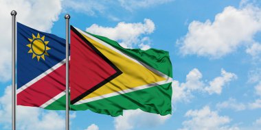 Namibya ve Guyana bayrağı birlikte beyaz bulutlu mavi gökyüzüne karşı rüzgarda sallayarak. Diplomasi kavramı, uluslararası ilişkiler.