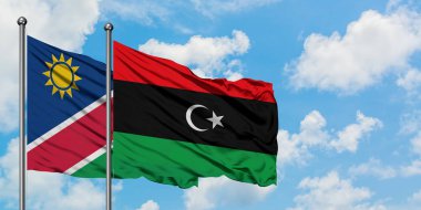 Namibya ve Libya bayrağı birlikte beyaz bulutlu mavi gökyüzüne karşı rüzgarda sallayarak. Diplomasi kavramı, uluslararası ilişkiler.