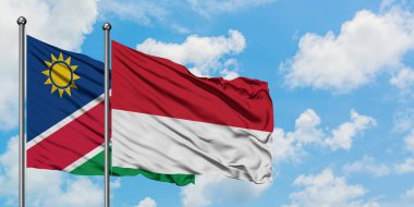 Namibya ve Monako bayrağı birlikte beyaz bulutlu mavi gökyüzüne karşı rüzgarda sallayarak. Diplomasi kavramı, uluslararası ilişkiler.