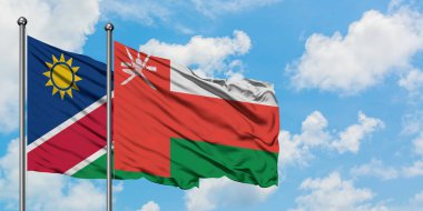 Namibya ve Umman bayrağı birlikte beyaz bulutlu mavi gökyüzüne karşı rüzgarda sallayarak. Diplomasi kavramı, uluslararası ilişkiler.