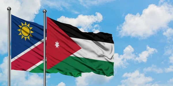 Bandera de Namibia y Jordania ondeando en el viento contra el cielo azul nublado blanco juntos. Concepto diplomático, relaciones internacionales . — Foto de Stock