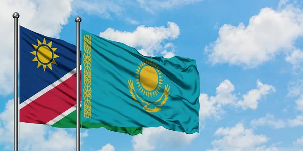 Drapeau de Namibie et du Kazakhstan agitant dans le vent contre ciel bleu nuageux blanc ensemble. Concept de diplomatie, relations internationales . — Photo