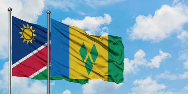 La Namibie et Saint-Vincent-et-les Grenadines battent ensemble dans le vent contre un ciel bleu nuageux blanc. Concept de diplomatie, relations internationales . — Photo