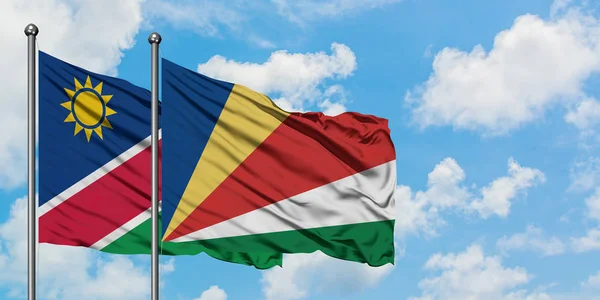 Drapeau namibien et seychellois agitant dans le vent contre le ciel bleu nuageux blanc ensemble. Concept de diplomatie, relations internationales . — Photo