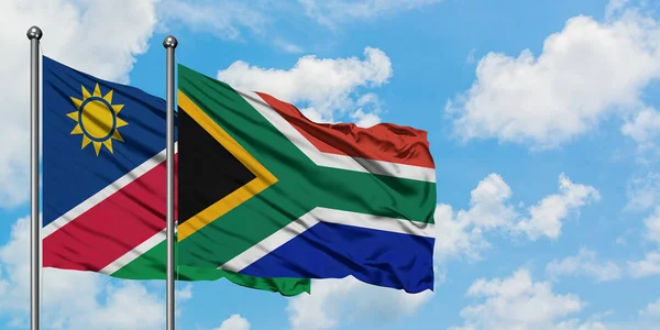 Namibie a Jihoafrická vlajka mávali ve větru proti bíle zatažené modré obloze. Diplomacie, mezinárodní vztahy. — Stock fotografie
