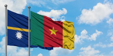 Nauru ve Kamerun bayrağı birlikte beyaz bulutlu mavi gökyüzüne karşı rüzgarda sallayarak. Diplomasi kavramı, uluslararası ilişkiler.