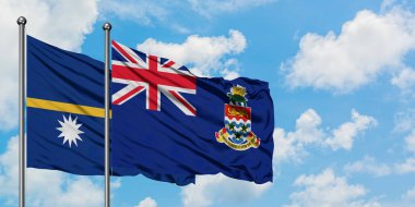 Nauru ve Cayman Adaları bayrağı birlikte beyaz bulutlu mavi gökyüzüne karşı rüzgarda sallayarak. Diplomasi kavramı, uluslararası ilişkiler.