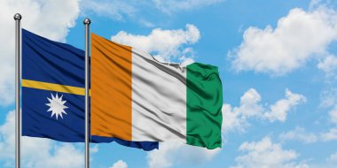 Nauru ve Fildişi Sahili bayrağı birlikte beyaz bulutlu mavi gökyüzüne karşı rüzgarda sallayarak. Diplomasi kavramı, uluslararası ilişkiler.