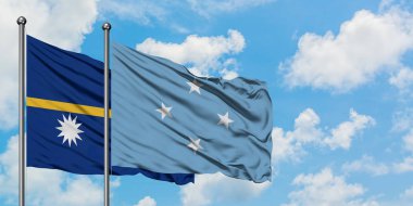 Nauru ve Mikronezya bayrağı birlikte beyaz bulutlu mavi gökyüzüne karşı rüzgarda sallayarak. Diplomasi kavramı, uluslararası ilişkiler.