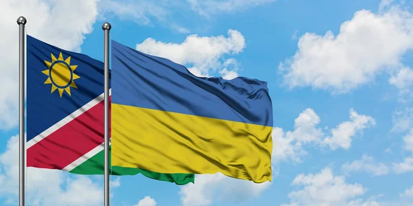 Drapeau de Namibie et d'Ukraine agitant dans le vent contre ciel bleu nuageux blanc ensemble. Concept de diplomatie, relations internationales . — Photo