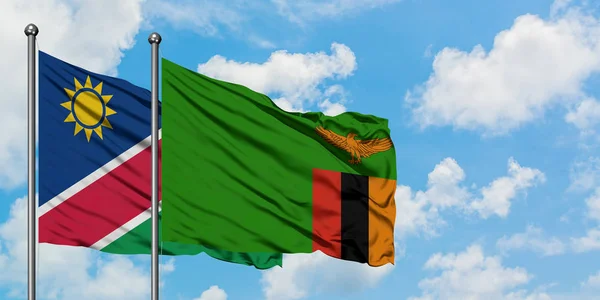 Bandera de Namibia y Zambia ondeando en el viento contra el cielo azul nublado blanco juntos. Concepto diplomático, relaciones internacionales . — Foto de Stock