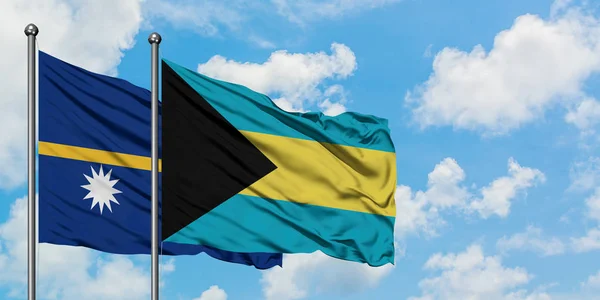 Nauru en de Bahama's vlag zwaaien in de wind tegen witte bewolkte blauwe hemel samen. Diplomatie concept, internationale betrekkingen. — Stockfoto