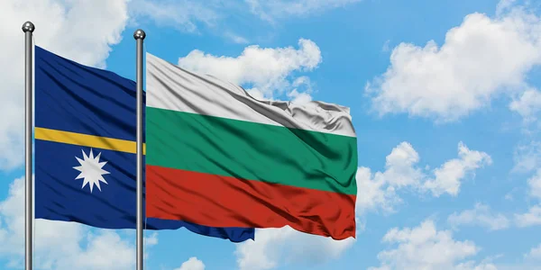 Bandera de Nauru y Bulgaria ondeando en el viento contra el cielo azul nublado blanco juntos. Concepto diplomático, relaciones internacionales . — Foto de Stock