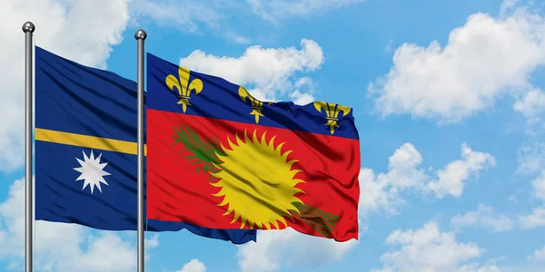 Bandera de Nauru y Guadalupe ondeando en el viento contra el cielo azul nublado blanco juntos. Concepto diplomático, relaciones internacionales . — Foto de Stock