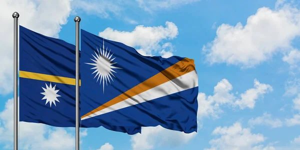 Bandeira de Nauru e Ilhas Marshall agitando no vento contra o céu azul nublado branco juntos. Conceito de diplomacia, relações internacionais . — Fotografia de Stock
