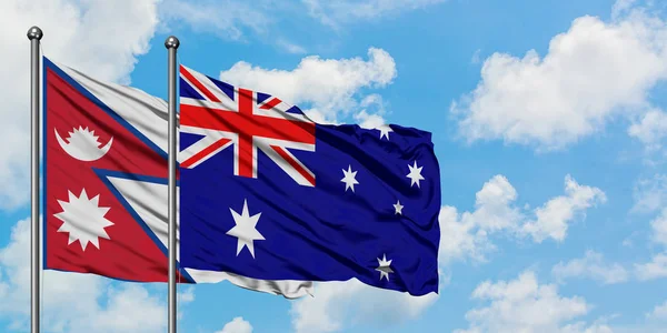 Bandera de Nepal y Australia ondeando en el viento contra el cielo azul nublado blanco juntos. Concepto diplomático, relaciones internacionales . —  Fotos de Stock