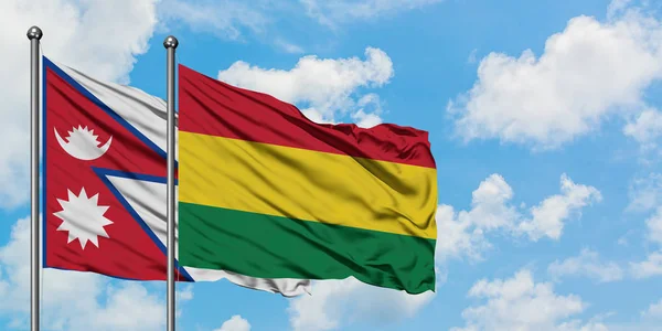 Bandera de Nepal y Bolivia ondeando en el viento contra el cielo azul nublado blanco juntos. Concepto diplomático, relaciones internacionales . — Foto de Stock
